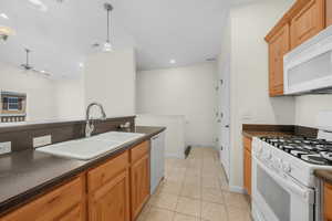 Kitchen with white appliances, decorative light fixtures, light tile patterned flooring, recessed lighting, and a ceiling fan