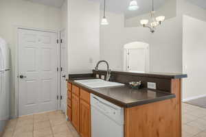 Kitchen with dishwasher, light tile patterned floors, a peninsula, pendant lighting, and freestanding refrigerator