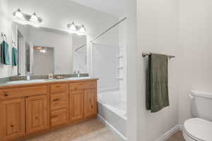 Full bathroom featuring light tile patterned floors, shower / washtub combination, double vanity, and a ceiling fan