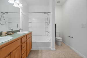 Full bath featuring light tile patterned flooring, shower / washtub combination, and double vanity