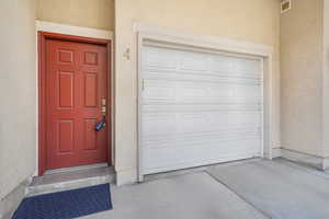 Property entrance featuring stucco siding and a garage