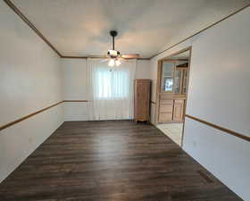 Unfurnished room featuring a textured ceiling, ceiling fan, ornamental molding, and wood finished floors