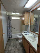 Full bath featuring vanity, shower / bath combo with shower curtain, toilet, and a textured ceiling