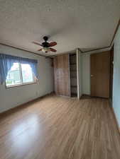 Unfurnished bedroom with light wood finished floors, a textured ceiling, baseboards, and a ceiling fan