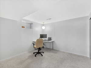 Carpeted bedroom/home office featuring a textured ceiling and baseboards