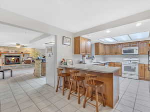 Kitchen featuring white appliances, a sink, light tile patterned floors, a breakfast bar, and a peninsula