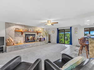 Living area with a tiled fireplace, a ceiling fan, recessed lighting, and tile patterned flooring