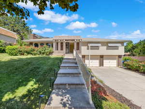 View of front of home with brick siding, an attached garage, driveway, and a front yard