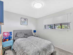 Carpeted bedroom with a textured ceiling and baseboards
