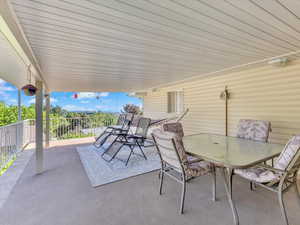 View of patio with outdoor dining area and a balcony