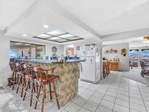 Kitchen featuring freestanding refrigerator, a breakfast bar, light tile patterned floors, a peninsula, and recessed lighting