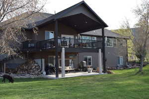 Back of property with a patio, a deck, and a lawn