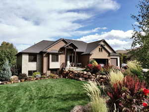 View of front of house featuring an attached garage, a front lawn, and brick siding