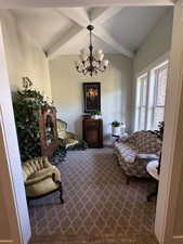 Sitting room with a chandelier, beamed ceiling, and dark carpet