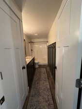 Full bath with a shower, vanity, a textured ceiling, wood finished floors, and toilet