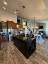Kitchen featuring appliances with stainless steel finishes, dark wood-style floors, a stone fireplace, a textured ceiling, and a chandelier
