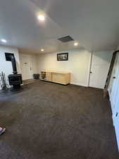 Unfurnished living room with a wood stove, recessed lighting, dark colored carpet, and baseboards