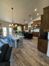 Dining area featuring a chandelier, dark wood finished floors, vaulted ceiling, and recessed lighting