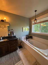 Full bath with vanity, a garden tub, and baseboards