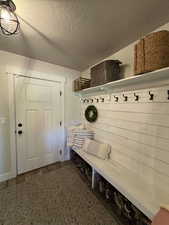 Mudroom with a textured ceiling, baseboards, and wood finished floors