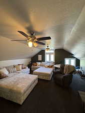 Bedroom featuring a textured ceiling, lofted ceiling, carpet, and ceiling fan
