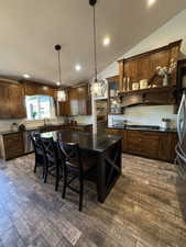 Kitchen featuring stainless steel appliances, dark countertops, recessed lighting, lofted ceiling, and a textured ceiling