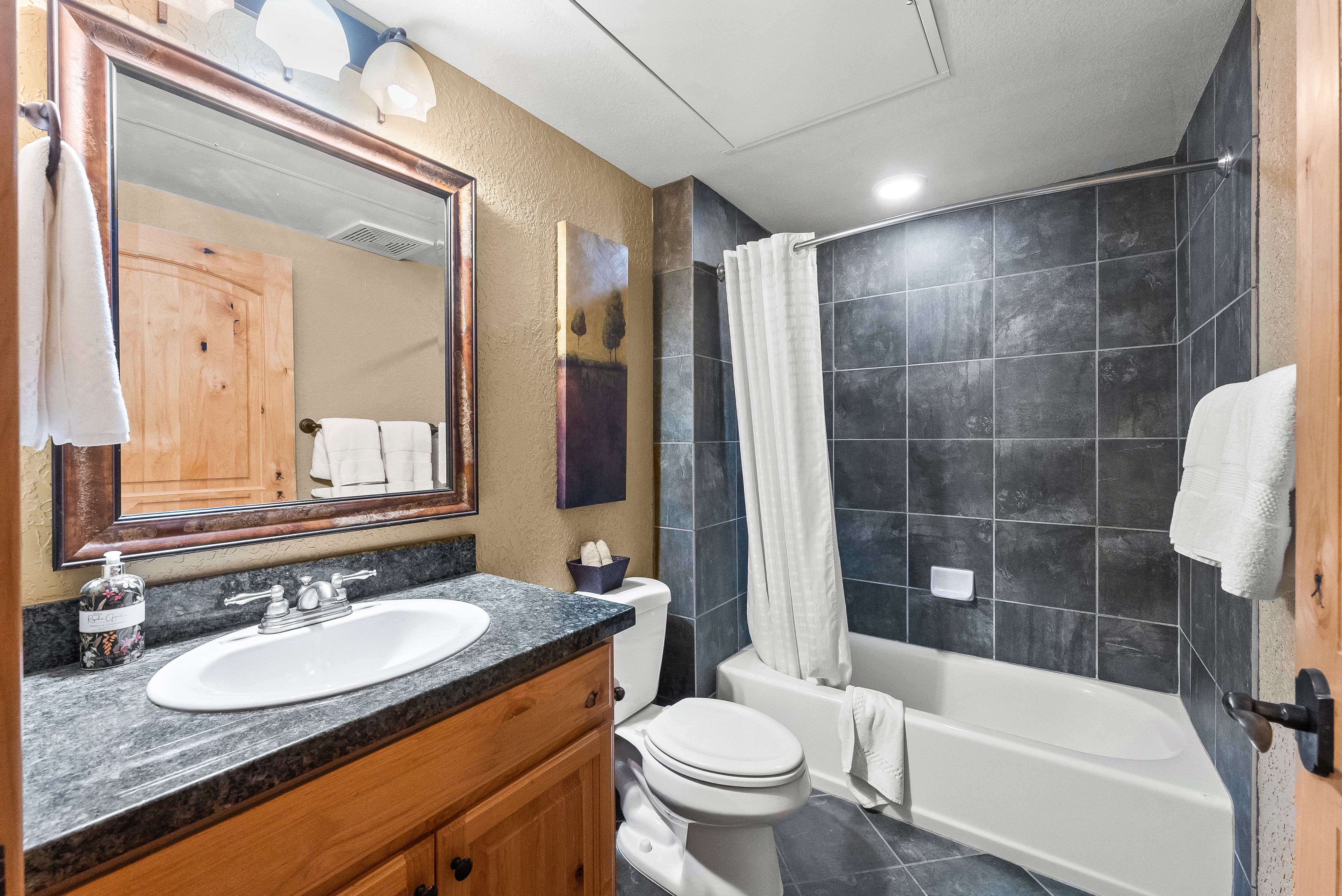 Full bathroom featuring vanity, a textured wall, shower / tub combo, toilet, and tile patterned floors