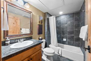 Full bathroom featuring vanity, a textured wall, shower / tub combo, toilet, and tile patterned floors