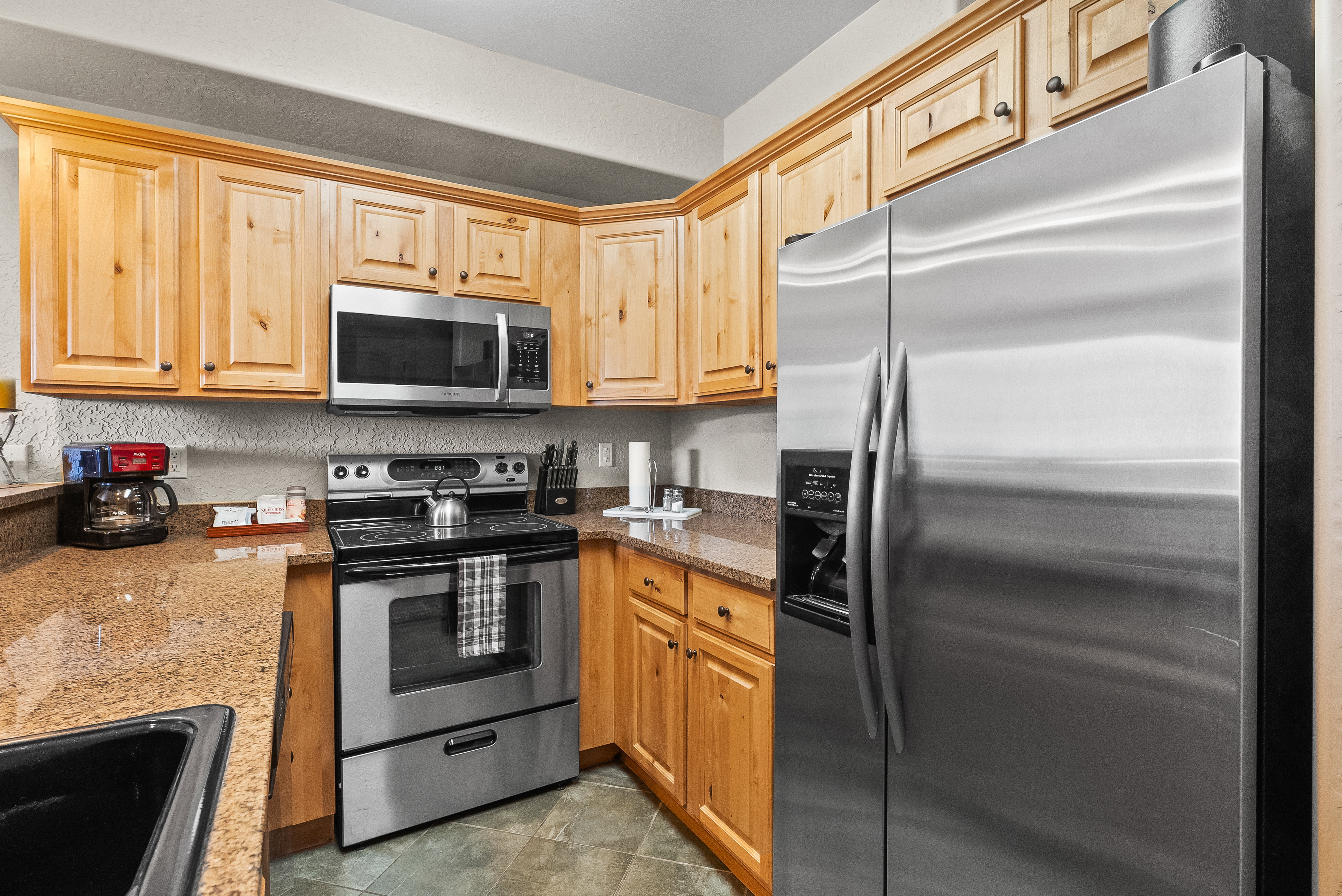 Kitchen with appliances with stainless steel finishes, a sink, and stone countertops