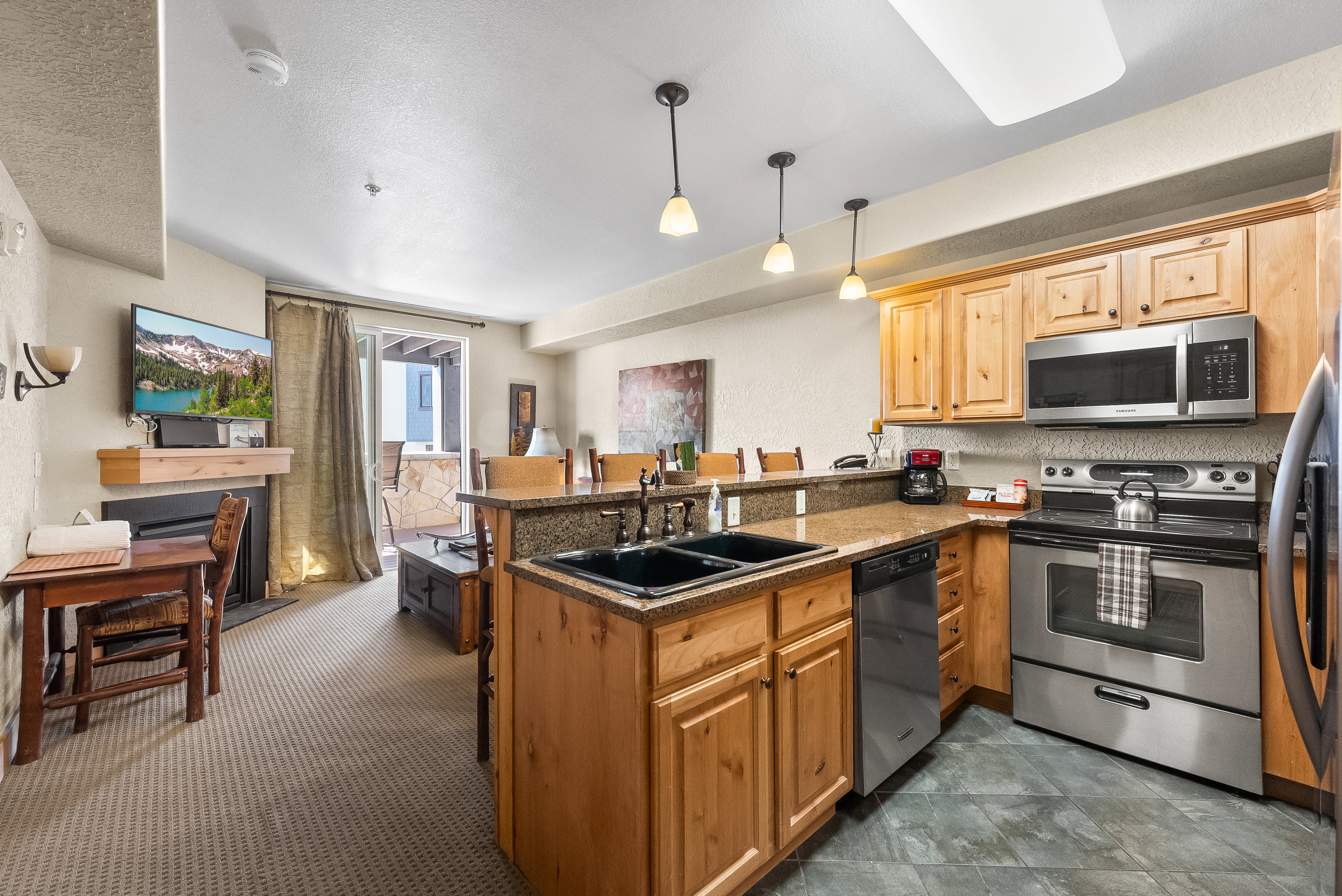 Kitchen featuring stainless steel appliances, a sink, a peninsula, decorative light fixtures, and a kitchen bar