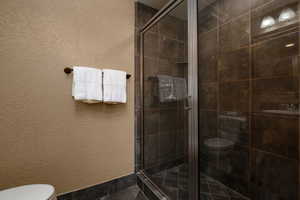 Bathroom featuring toilet and a stall shower