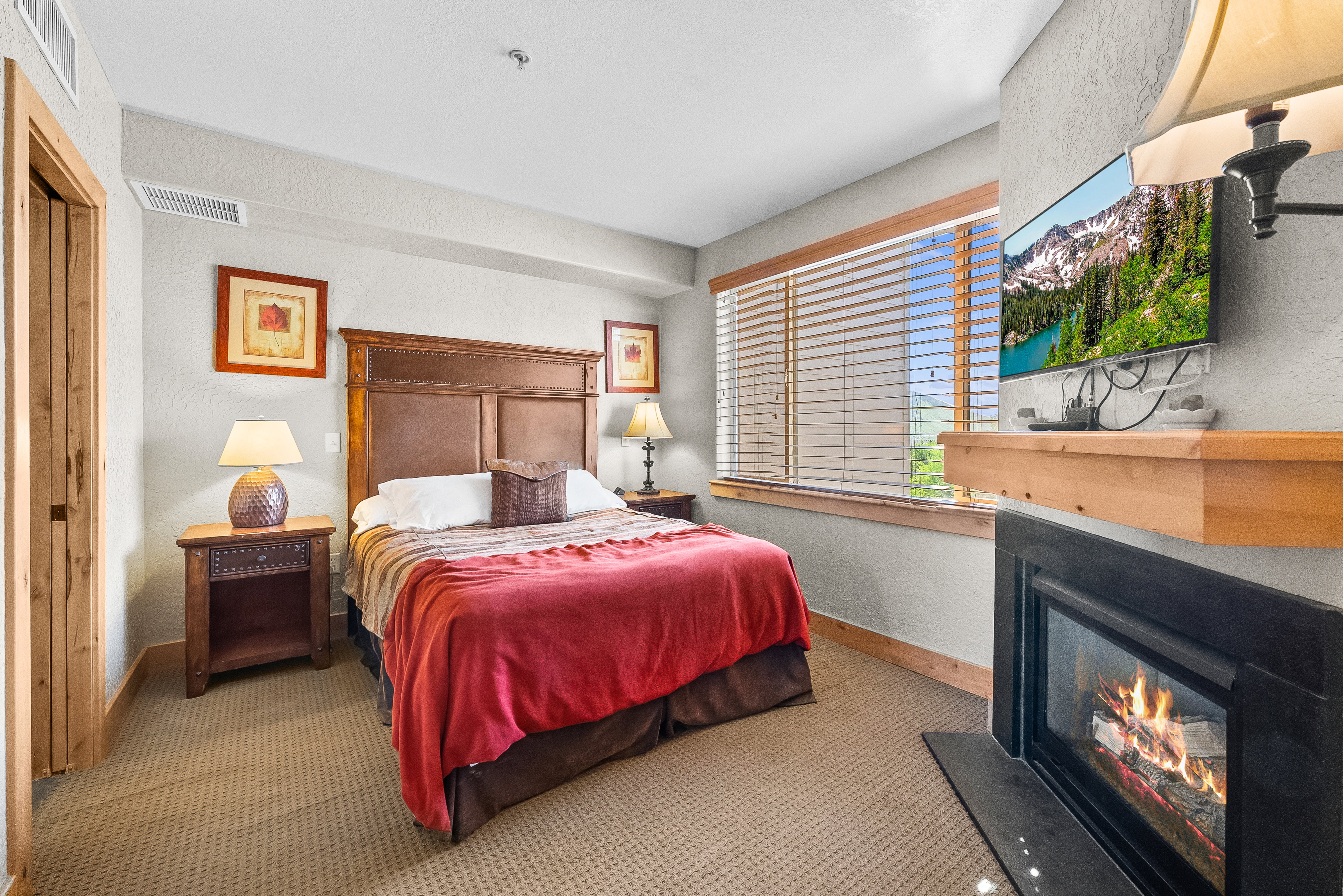 Carpeted bedroom with a glass covered fireplace, baseboards, and a textured wall