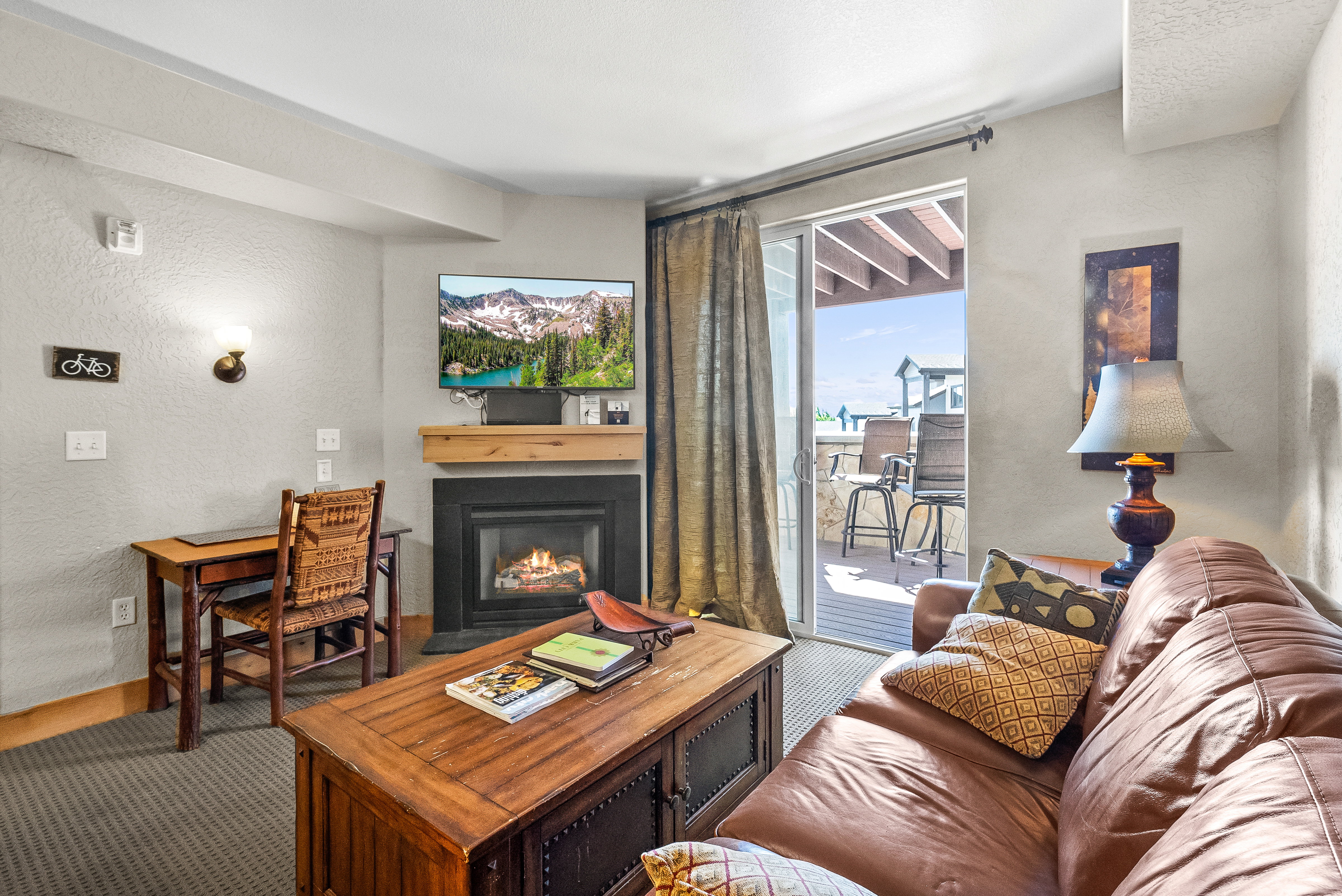 Living area with a glass covered fireplace, a textured wall, carpet flooring, and baseboards