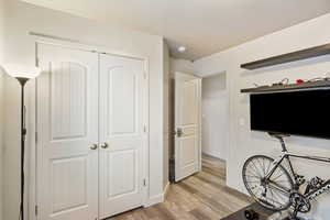 Bedroom with light wood-style floors, baseboards, and a closet