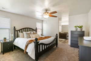 Bedroom featuring light carpet, ensuite bathroom, and a ceiling fan