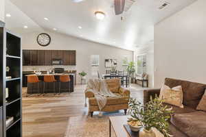 Living room featuring light wood-style flooring, vaulted ceiling, recessed lighting, and baseboards