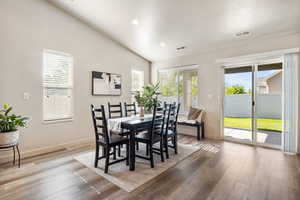 Dining area featuring wood finished floors, baseboards, lofted ceiling, recessed lighting, and a textured ceiling
