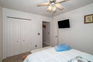 Carpeted bedroom with a closet, a ceiling fan, and baseboards