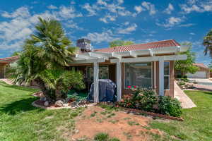 Back of property with a pergola, a yard, a tiled roof, and stucco siding