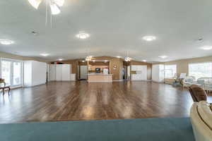 Living room featuring ceiling fan, dark wood-type flooring, lofted ceiling, a textured ceiling, and baseboards