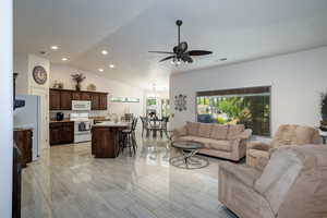 Living area featuring a ceiling fan, recessed lighting, a chandelier, vaulted ceiling, and light marble finish floors