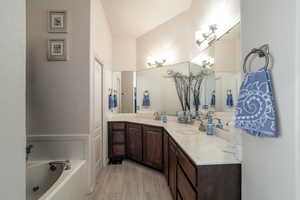 Bathroom with a bathtub, double vanity, and marble look tiles