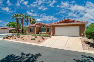 View of front facade with a garage, driveway, a tile roof, and stucco siding