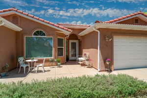Property entrance featuring stucco siding, a tile roof, and a garage