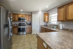 Kitchen featuring stainless steel appliances, brown cabinets, a sink, and recessed lighting
