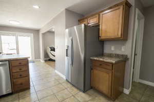 Kitchen featuring stainless steel appliances, brown cabinets, baseboards, light tile patterned floors, and recessed lighting