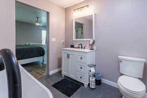 Ensuite bathroom featuring vanity, a freestanding tub, baseboards, toilet, and tile patterned floors