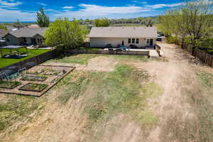 Rear view of house with a vegetable garden, a wooden deck, and dirt driveway