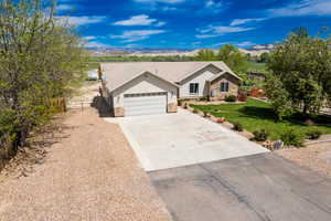 Ranch-style home with stone siding, a garage, concrete driveway, and a mountain view
