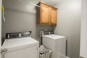 Laundry room featuring cabinet space, washing machine and dryer, and a textured ceiling